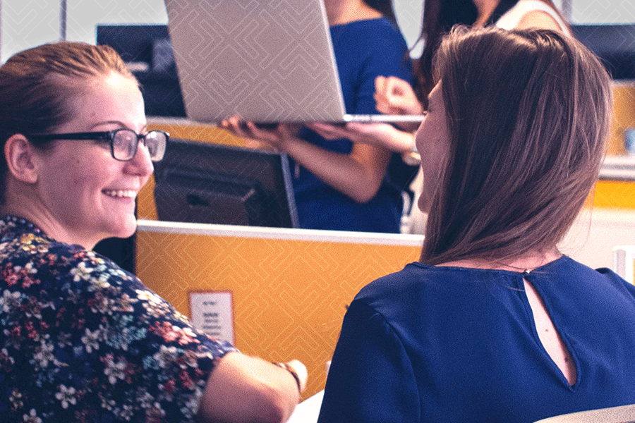 two women talking at a desk