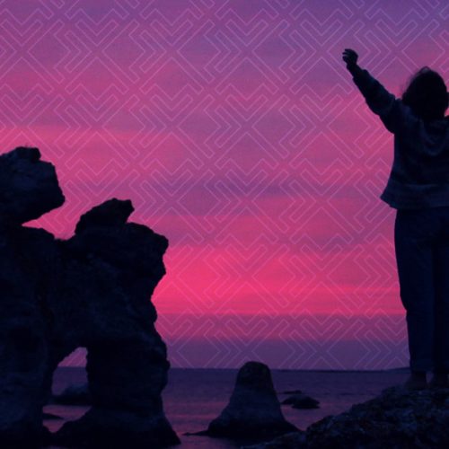 Person standing on top of mountain looking at water