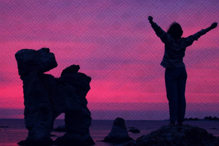 Person standing on top of mountain looking at water