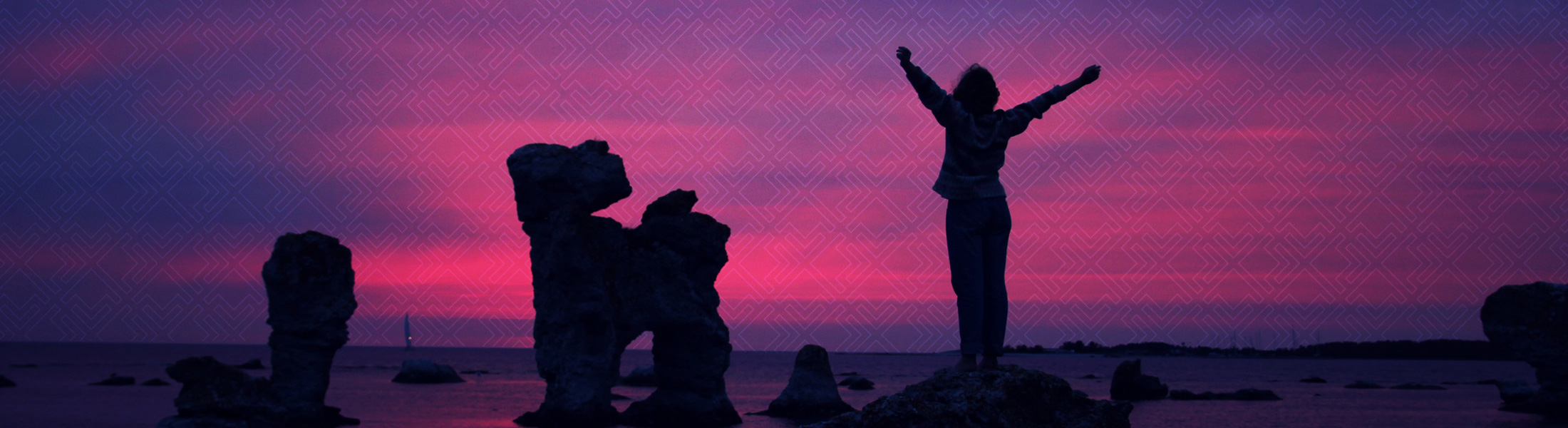 Person standing on top of mountain looking at water