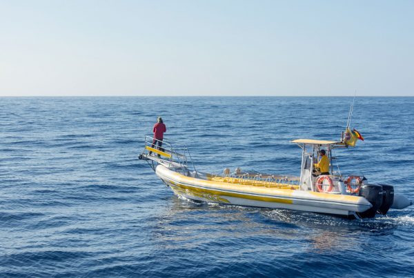 Yellow and White Boat alone in the Ocean with two fishermen