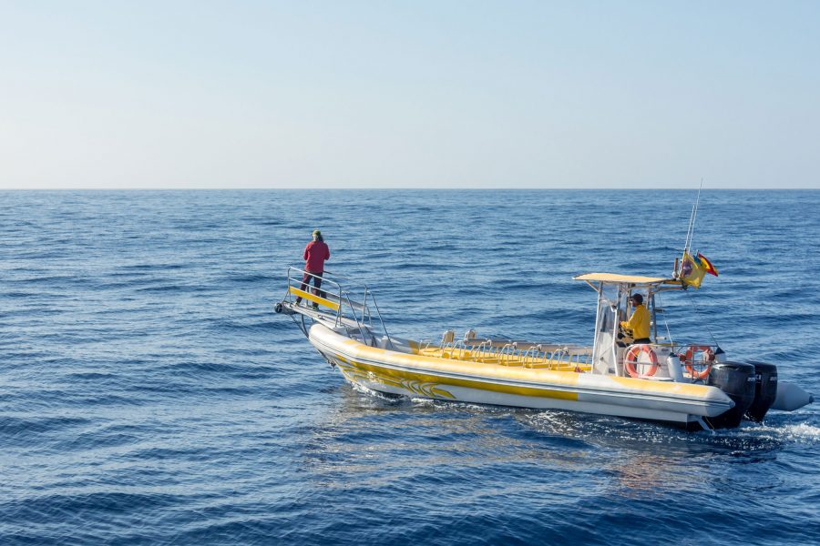 Yellow and White Boat alone in the Ocean with two fishermen